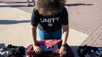 photo of student wearing t-shirt that says "unity" folding a tshirt that says "BTHO hate"