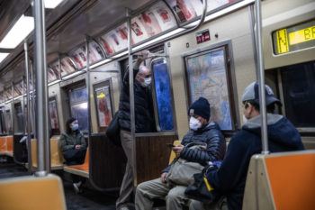 People wearing face masks sitting on subway