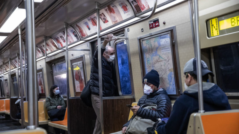 People wearing face masks sitting on subway