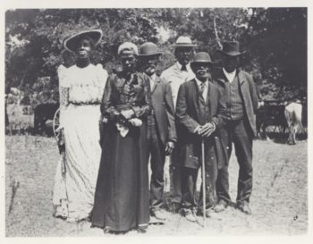 black and white photograph of a small group of african americans posing for a photograph wearing formal clothes