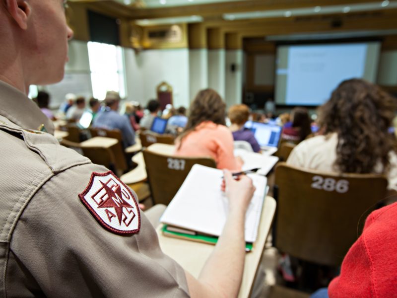 image from behind of a cadet taking notes in a teaching theatre among other students