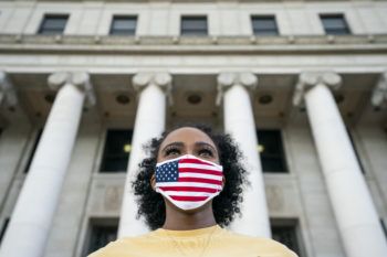 female student wearing a american flag cloth mask standing in front of tamu administration building