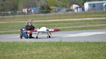 student kneeling on runway next to airplane