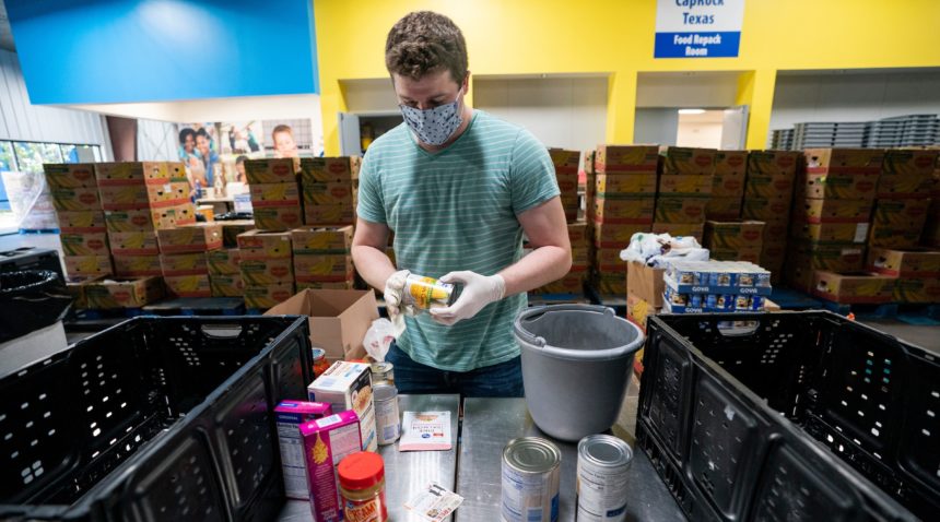 a man in a blue t shirt and face mask handles canned goods in a warehouse