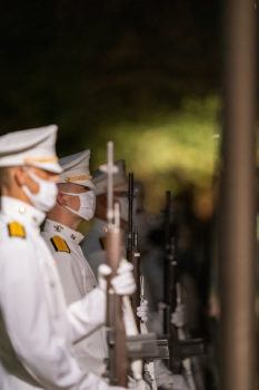 Multiple Corps of cadets wearing their all-white uniform and holding their rifles at the ready in a ceremonial way for the Silver Taps tradition