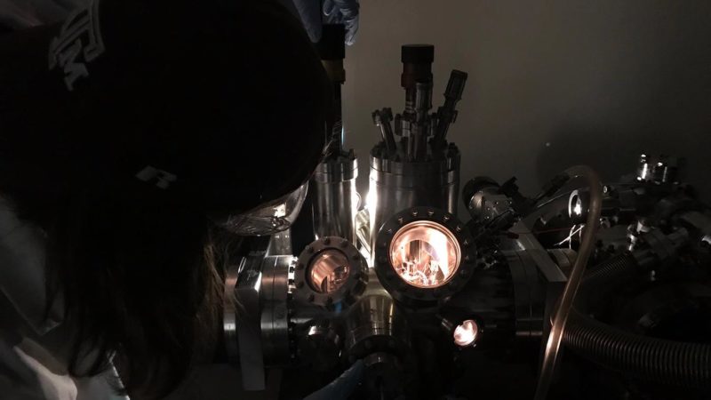 dark image of a student bending over a microscope