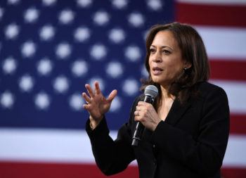 kamala harris speaking into a microphone in front of the U.S. flag