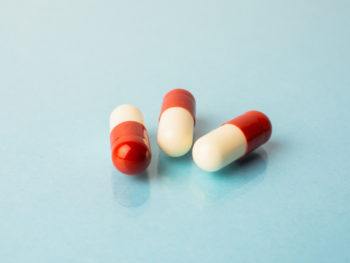 three red and white pills against a blue background