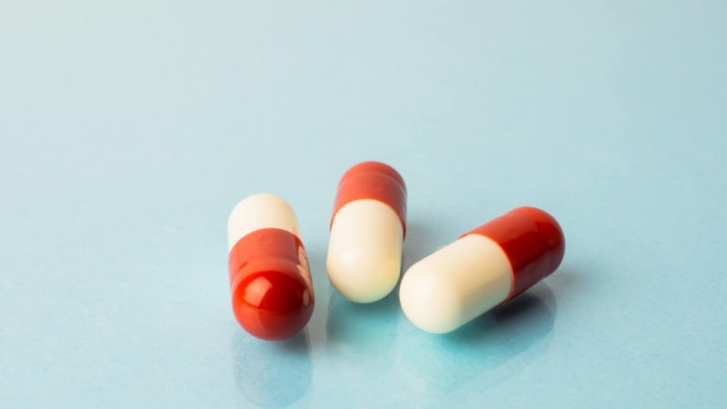 three red and white pills against a blue background