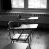 black and white photo of empty desks in a classroom
