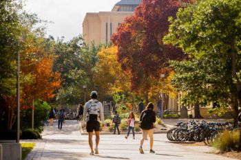 students walk on campus with fall foliage