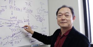portrait of professor writing equations on a white board