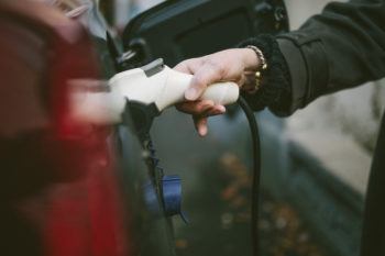 Hand of senior woman charging electric car