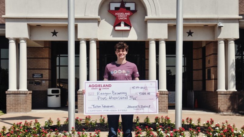 student standing outside with a large check with support aggieland graphic overlay