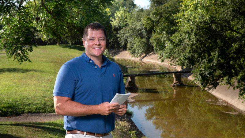 portrait of galen newman outside next to a drainage ditch filled with water