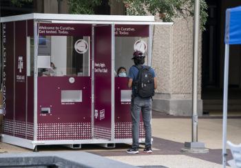 a student standing in front of a COVID-19 testing kiosk on campus