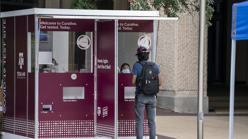 a student standing in front of a COVID-19 testing kiosk on campus