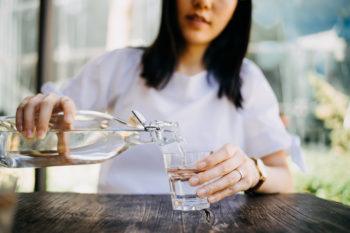Woman pouring water from bottle into a glass