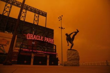 exterior of baseball stadium with orange glow in the background from wildfire