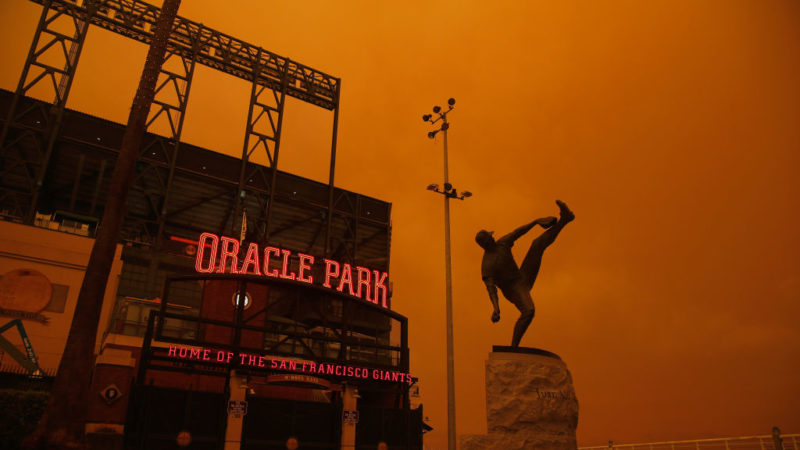 exterior of baseball stadium with orange glow in the background from wildfire