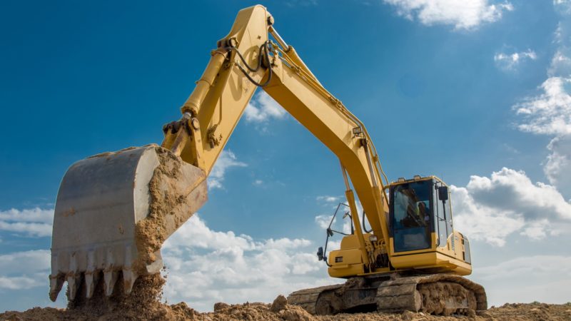 excavator on construction site in front of blue sky