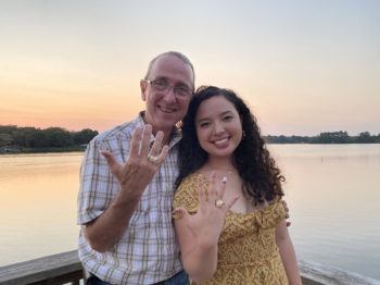 Kenneth "Kip" Martin '86 and his daughter Vivian Martin '21 pose before a lake, showing off their Aggie rings