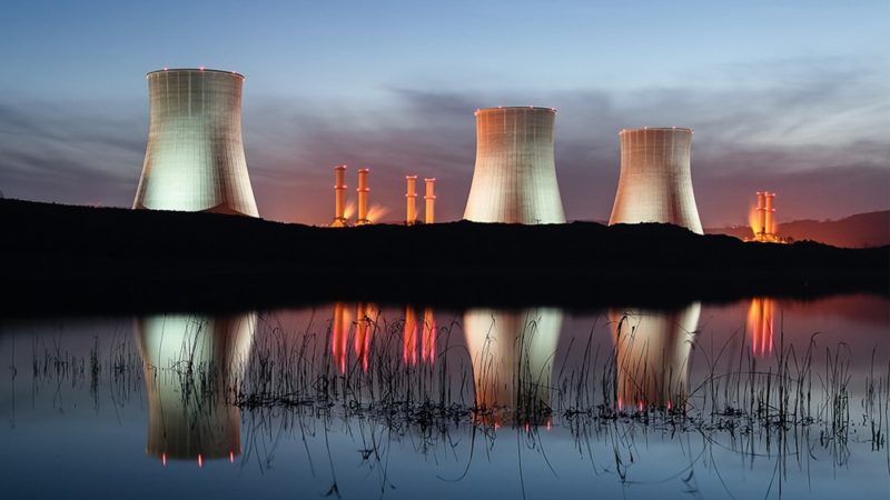 nuclear power plant at night with reflection on water