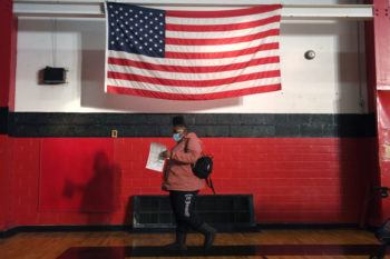 woman walks underneath an american flag hanging in a gymnasium