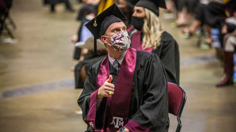 graduates sitting in reed arena at commencement wearing face coverings
