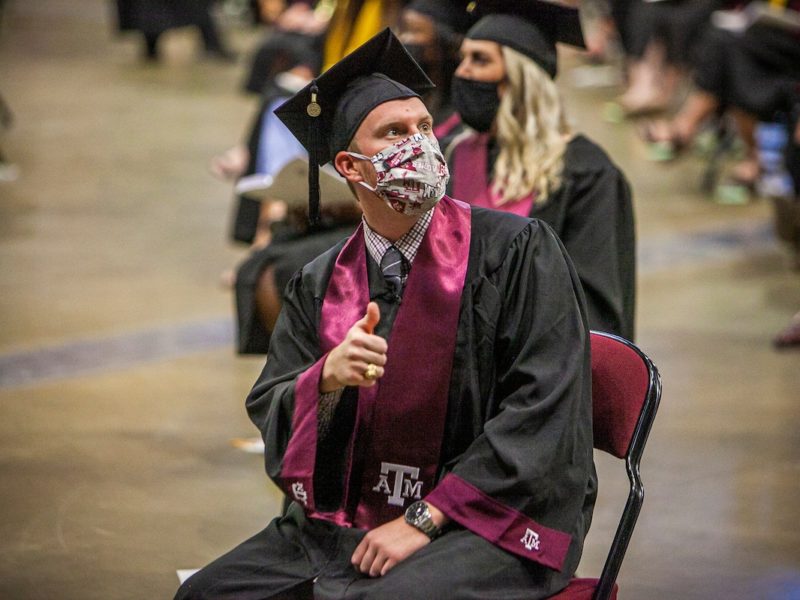 graduates sitting in reed arena at commencement wearing face coverings