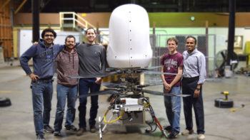 group photo of team standing next to their machine