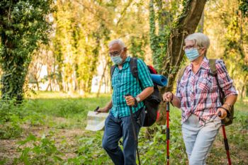 Senior couple on a walk in the woods wearing protective masks