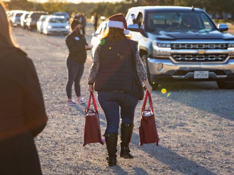 a photo of volunteers handing out care packages at a drive thru distribution event