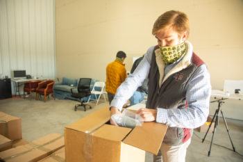 student wearing face mask in a warehouse loading boxes