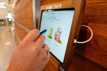 close up of man's hand holding a stylus at self-order dining tablet