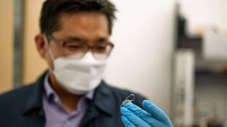 professor looking down at tiny device in his hand