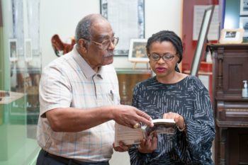 wayne sadberry shows a book to andrea roberts in a museum