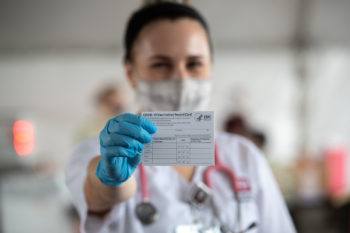 female student holds out a vaccination card