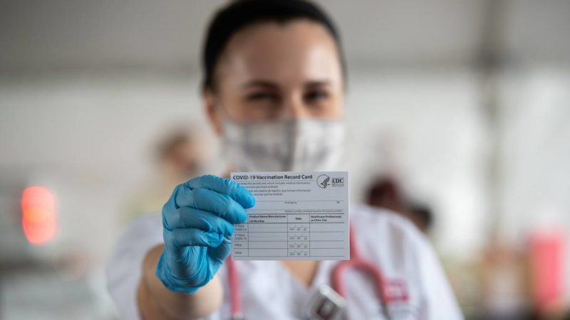 female student holds out a vaccination card