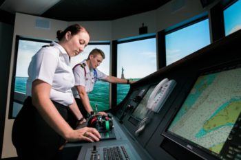 two student cadets in uniform using a ship simulator