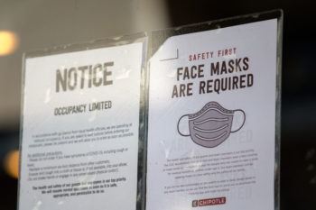 two signs taped to a store window saying "face masks are required"
