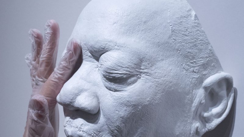 a hand touching a cast resin mask of Bobby Blue Bland