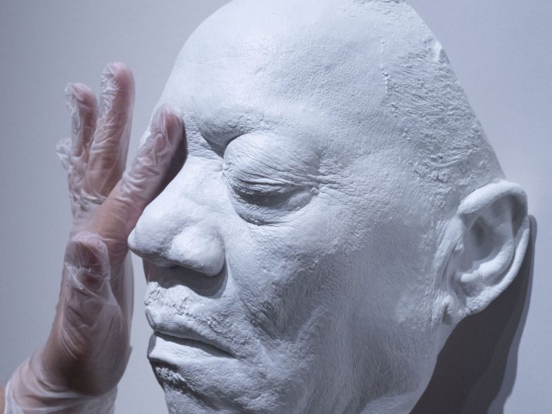 a hand touching a cast resin mask of Bobby Blue Bland