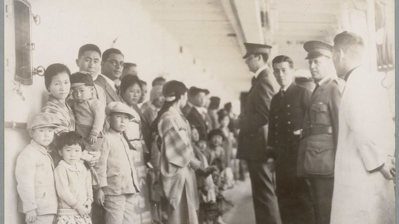 black and white photograph of men inspecting asian immigrants on a boat
