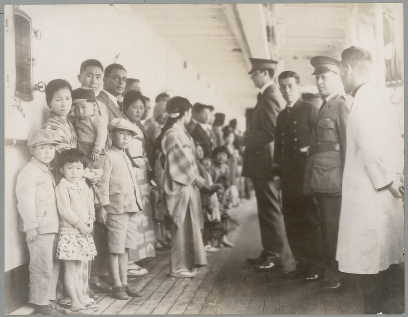 black and white photograph of men inspecting asian immigrants on a boat