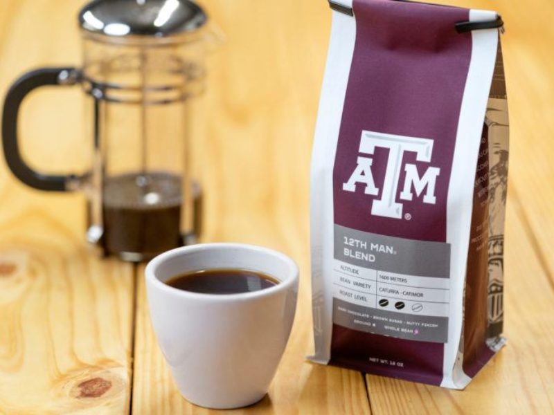 photo of a french press and coffee cup next to a bag of coffee with a&m logo