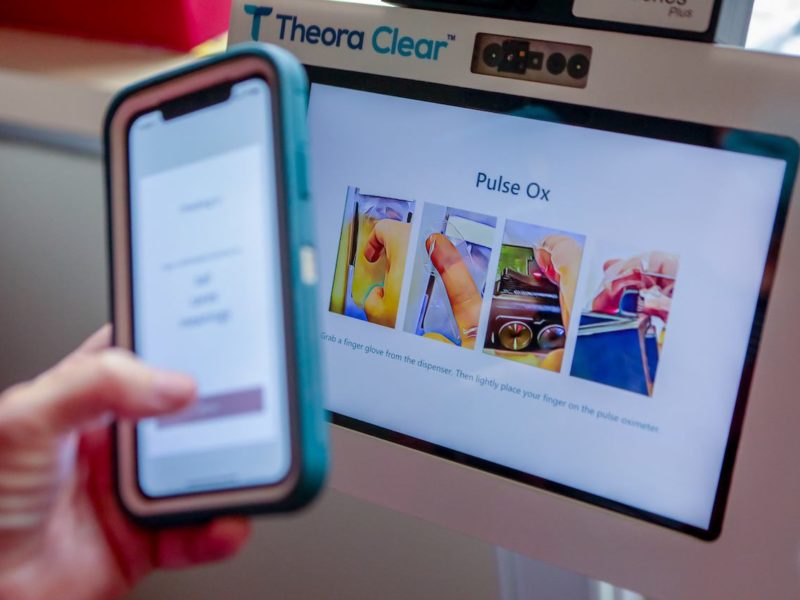 close up image of a person holding their cell phone up to the screen of a kiosk