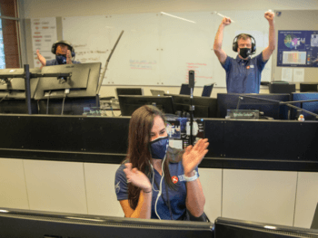 photo of student clapping in nasa control room with two men cheering in background