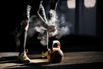 photo of the lower half of a mn's body s he prepares to exercise with a kettle bell