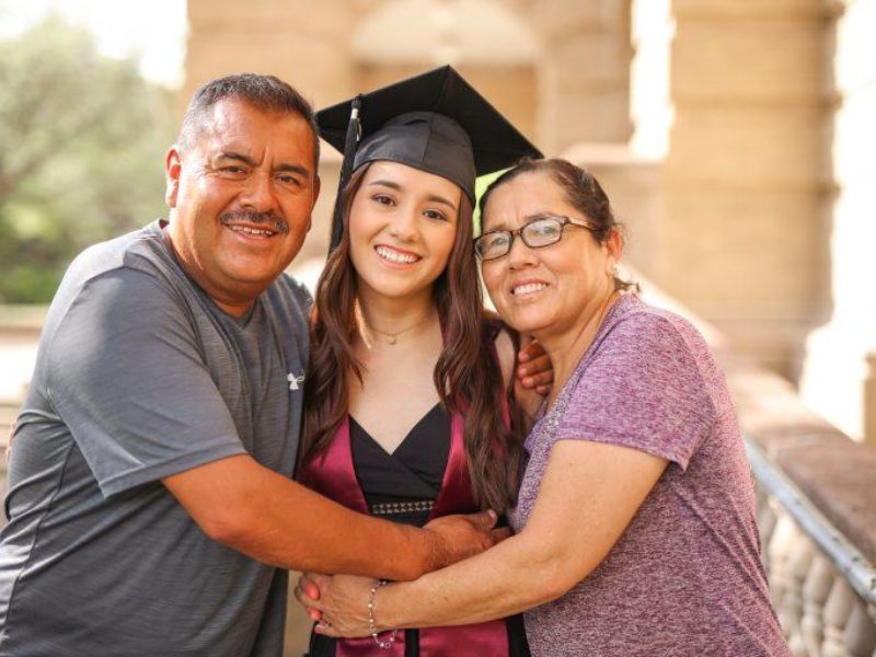 Lizeth Parra wearing a cap and gown posing with her parents